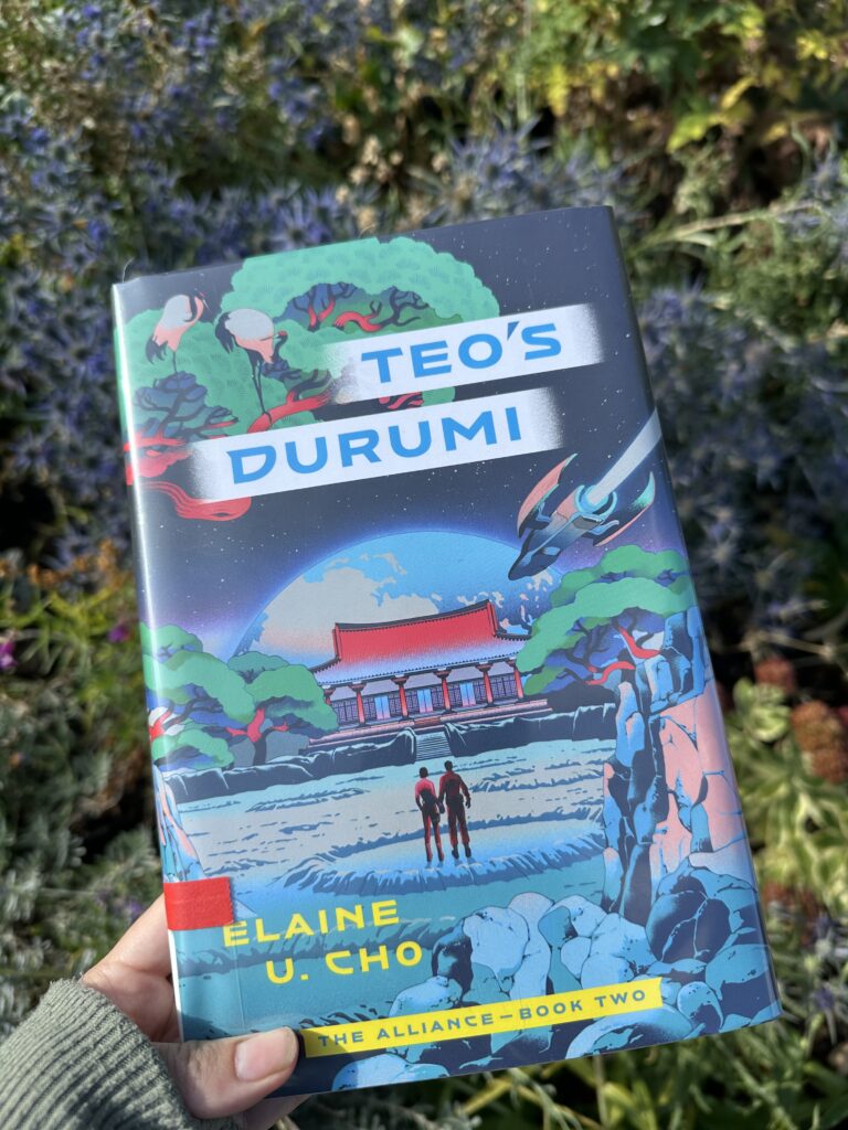 The cover of Teo's Durumi by Elaine U Cho shows two figures holding hands before a Japanese style pogoda with a space ship flying overhead