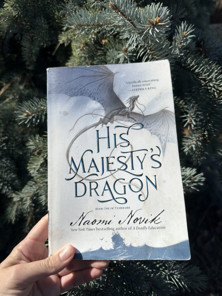 His Majesty's Dragon my Naomi Novik shows a dragon flying above a ship that tosses on the sea