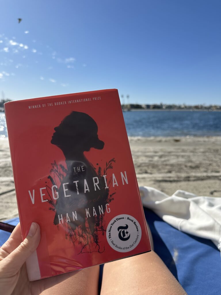 The cover of The Vegetarian by Han Kang shows a woman's silhouette gazing into the sky on a red background