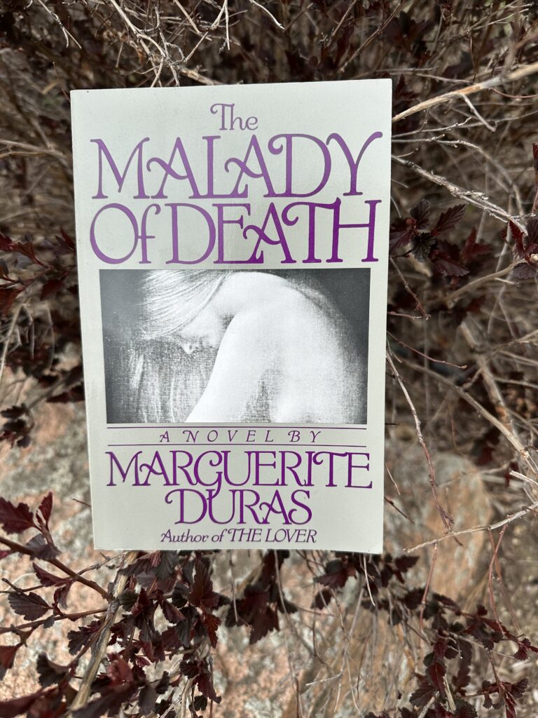 The cover of The Malady of Death by Marguerite Duras shows a black and white image of a woman in profile, hunched forward, her hair swept over one shoulder