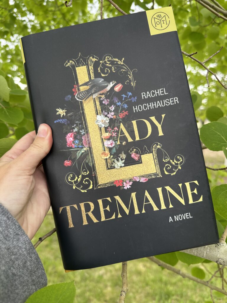 The cover of Lady Tremaine by Rachel Hockhauser shows gold words on a background of flowers. A falcon perches on the L