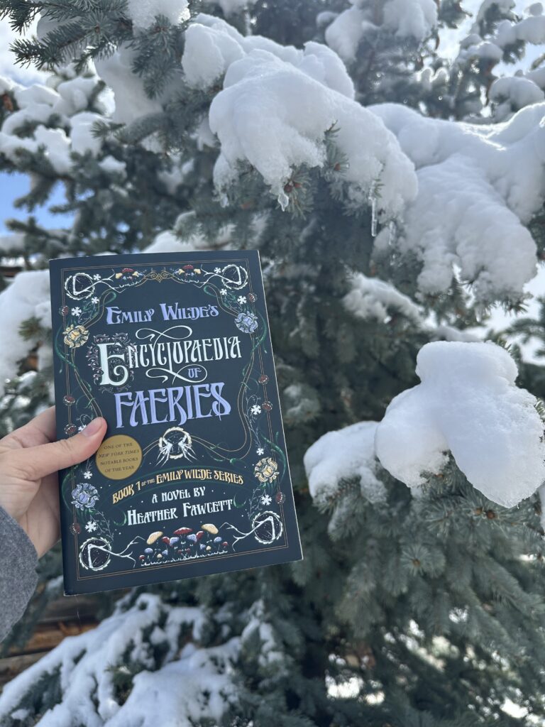 The cover of Emily Wilde's Encyclopaedia of Faeries shows the text surrounded by drawings of flowers, bones, and mushrooms