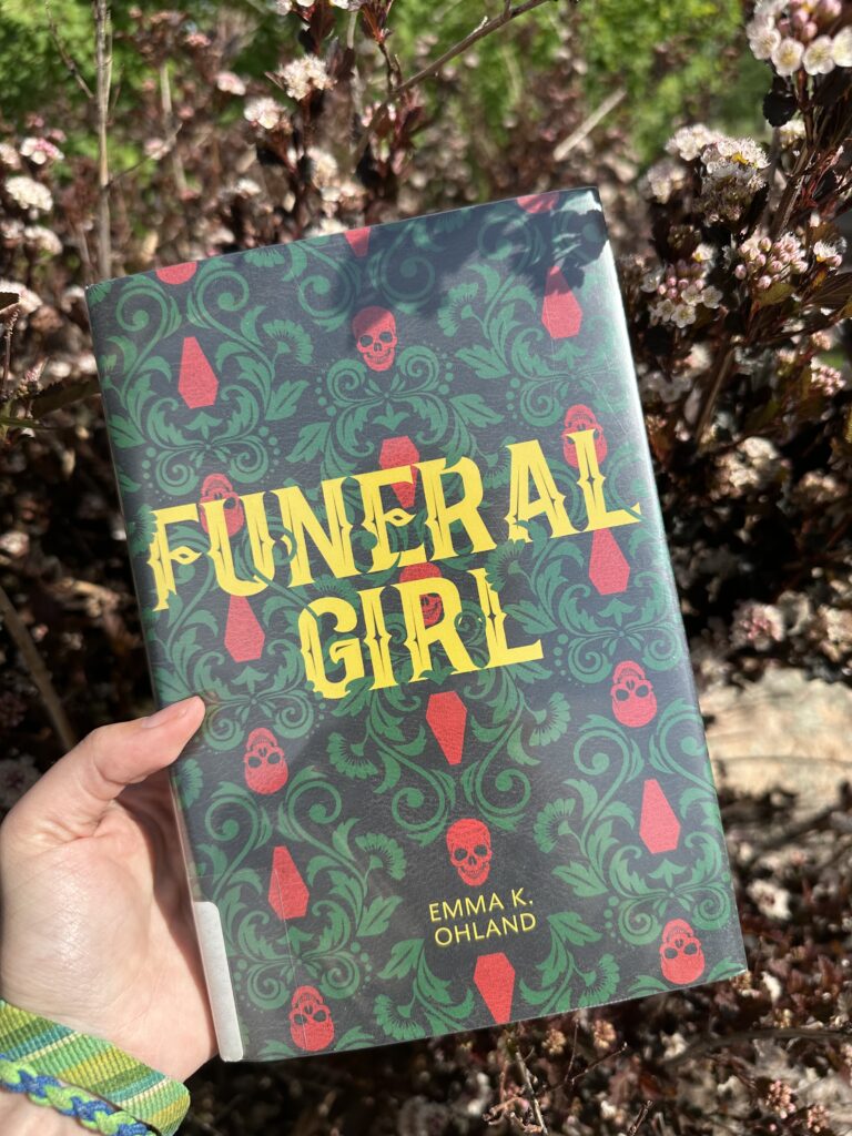 The cover of Funeral Girl shows a wallpaper style pattern of skulls, coffins, and flowers and leaves.