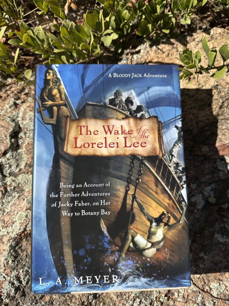 On the cover of The Wake of the Lorelei Lee, the prow of a ship with a figurehead in the shape of a girl holding a lyre. The anchor is emerging from the water and a girl is seated on it, waving